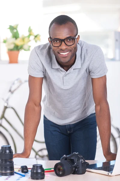 African man in casual wear leaning at the table with camera — Stock Photo, Image