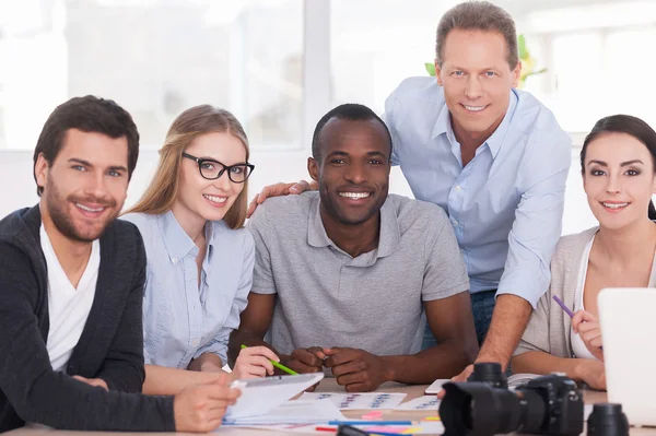 Discutiendo un nuevo proyecto juntos. Grupo de gente alegre de negocios sentados juntos en la mesa y discutiendo algo — Foto de Stock