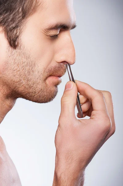 Man tweezing hair from nose. — Stock Photo, Image