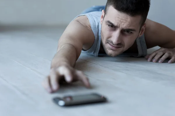 Uomo allungando la mano al telefono cellulare — Foto Stock