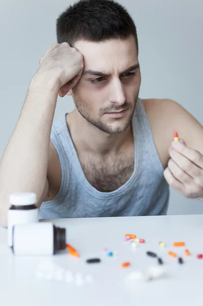 Frustrierter junger Mann schaut auf die Pillen — Stockfoto