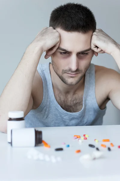 Gefrustreerd jonge man kijkend naar de pillen — Stockfoto