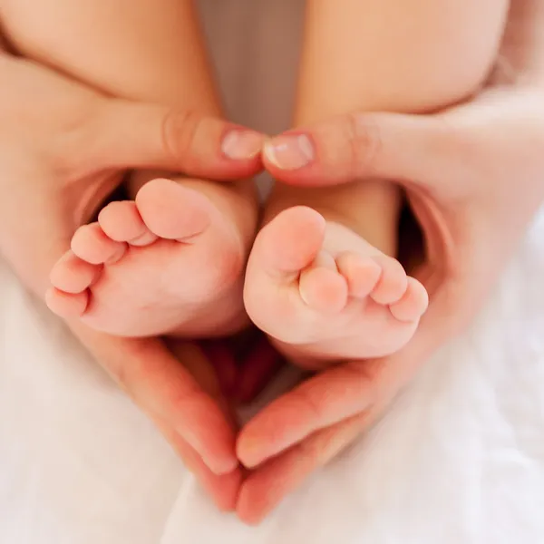 Mãe mãos tocando pernas do bebê — Fotografia de Stock