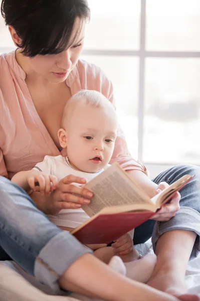 Madre che tiene in braccio bambino e libro di lettura — Foto Stock