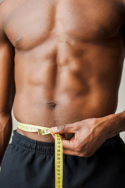 Homem negro muscular medindo sua cintura — Fotografia de Stock