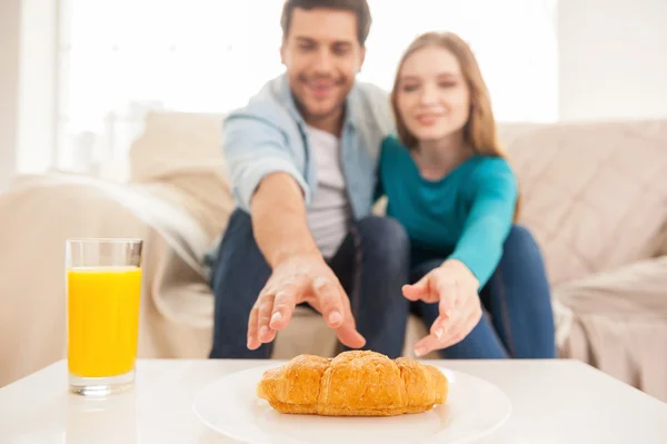 Couple stretching hands to the last croissant — Stock Photo, Image