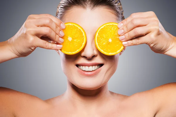 Woman holding pieces of orange in front of eyes — Stock Photo, Image