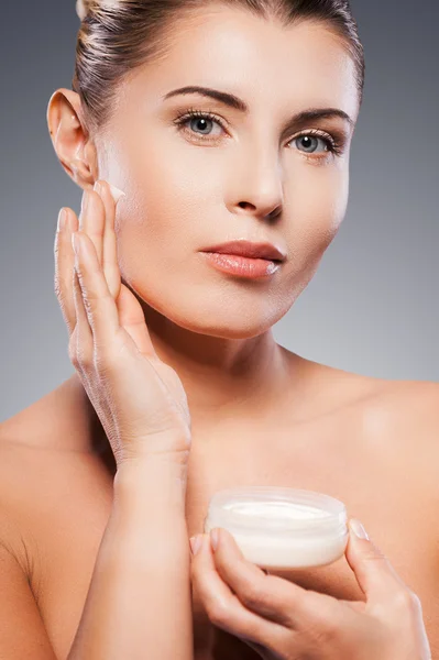 Mature woman spreading cream on face — Stock Photo, Image