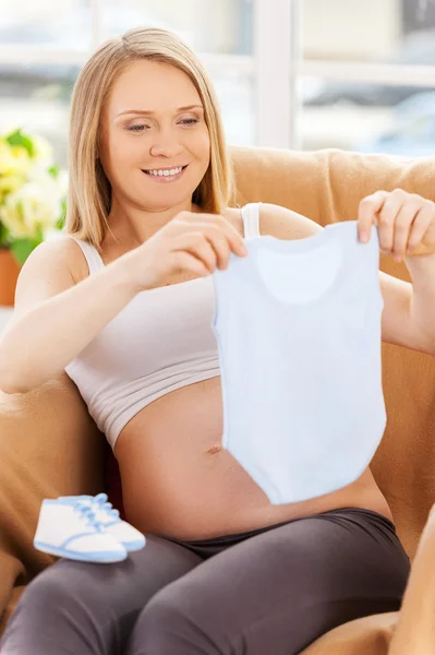 Mulher grávida com roupas de bebê . — Fotografia de Stock