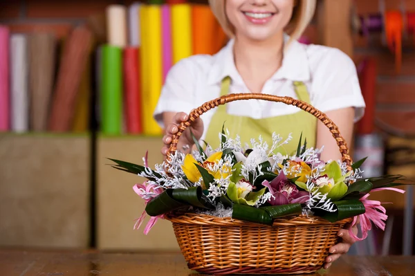 Mulher esticando cesta cheia de flores — Fotografia de Stock