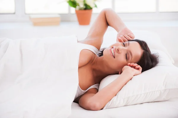 Woman lying in bed and stretching out — Stock Photo, Image