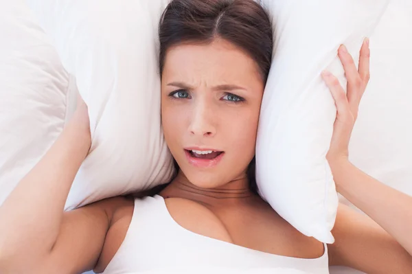 Woman covering ears by pillows — Stock Photo, Image