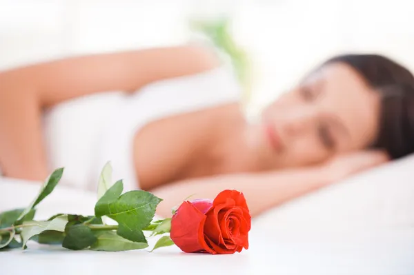 Mujer joven acostada en la cama con rosa roja —  Fotos de Stock