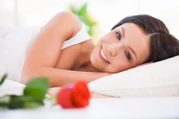 Young woman lying in bed with red rose — Stock Photo, Image