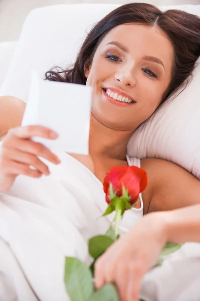 Woman lying in bed with red rose — Stock Photo, Image