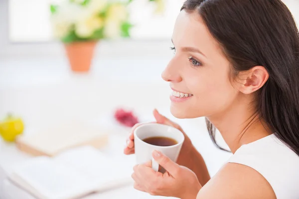 Femme assise dans son lit et tenant une tasse — Photo