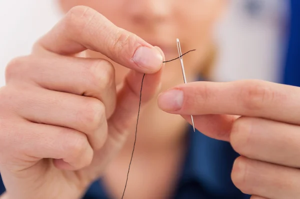 Woman pulling thread into needle — Stock Photo, Image