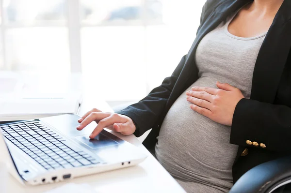 Zwangere vrouw die op laptop werkt. — Stockfoto