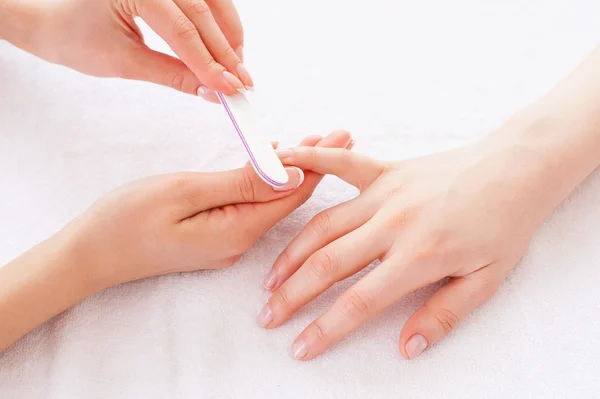 Beautician polishing female nails — Stock Photo, Image
