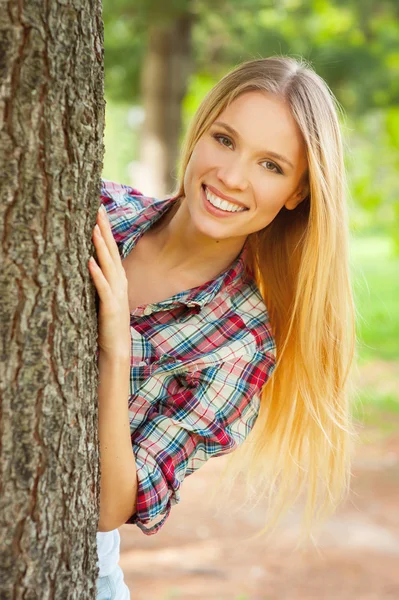 Vrouw op zoek uit de boom — Stockfoto