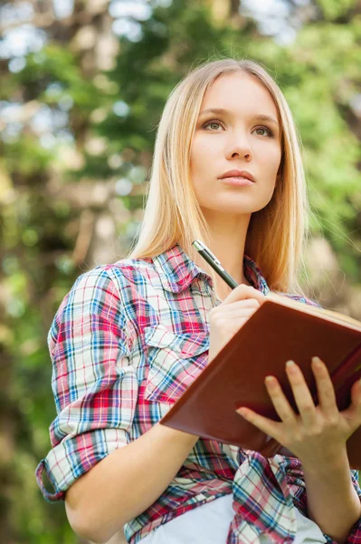 Mujer escribiendo algo en bloc de notas — Foto de Stock