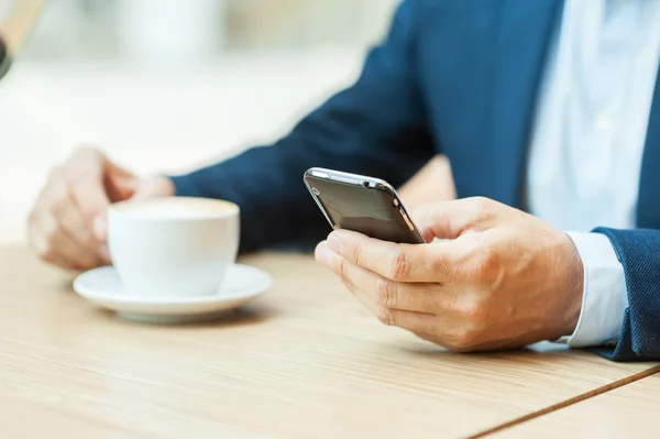 Homme en tenue de cérémonie buvant du café et tapant un message — Photo