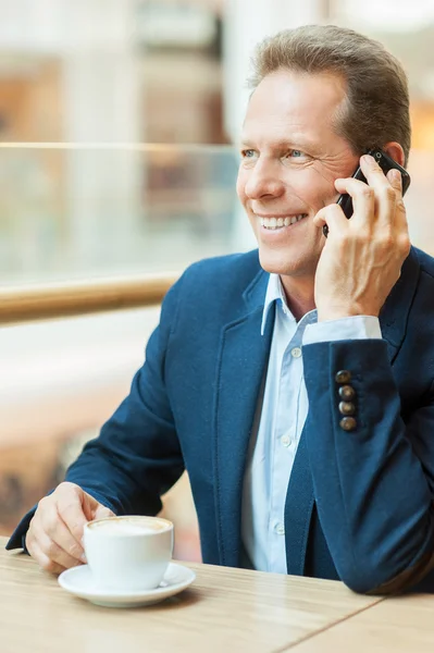 Muž pije kávu a mluví po telefonu — Stock fotografie