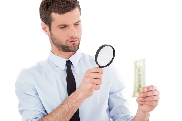 Man looking through a magnifying glass at the paper currency — Stock Photo, Image