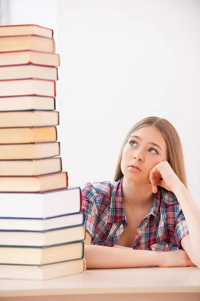 Adolescente chica buscando en gran pila de libros — Foto de Stock