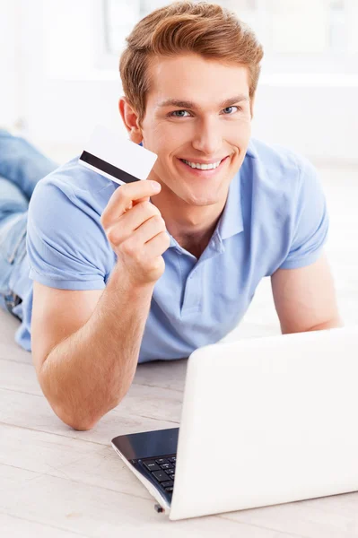 Man working on laptop and holding credit card — Stock Photo, Image