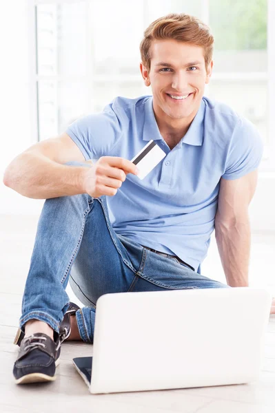 Hombre trabajando en el ordenador portátil y mostrando crédito — Foto de Stock