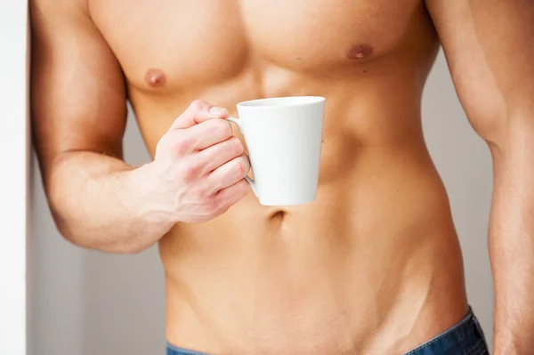 Muskularny mężczyzna trzyma kubek kawy — Zdjęcie stockowe