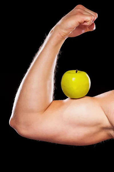 Svalnatý muž ukazuje jeho biceps s apple — Stock fotografie