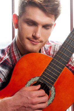 Adam akustik gitar çalıyor.