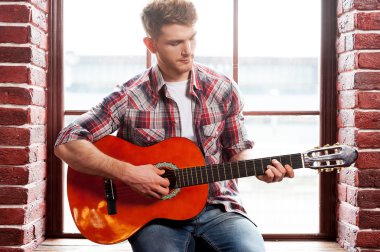 Adam akustik gitar çalıyor.