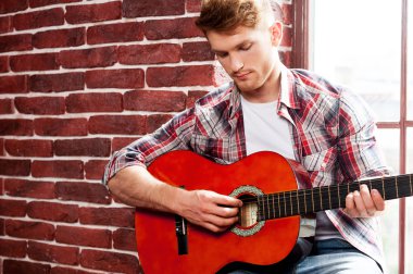 Adam akustik gitar çalıyor.