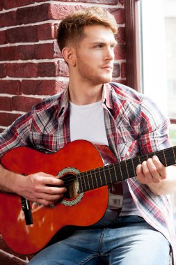 Adam akustik gitar çalıyor.