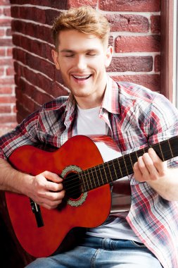 Gitar çalan ve şarkı söyleyen adam