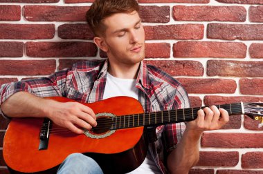 Adam akustik gitar çalıyor.