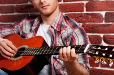 Adam akustik gitar çalıyor.