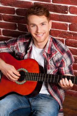Adam akustik gitar çalıyor.