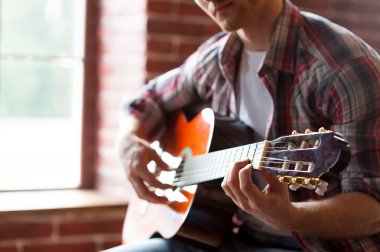 Adam akustik gitar çalıyor.