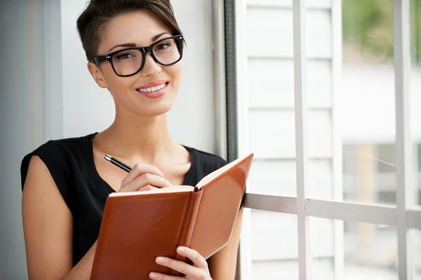 Mulher segurando bloco de notas e sorrindo — Fotografia de Stock