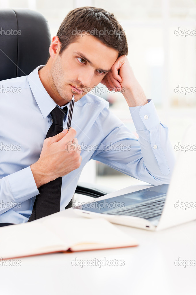 Man in shirt and tie looking at laptop