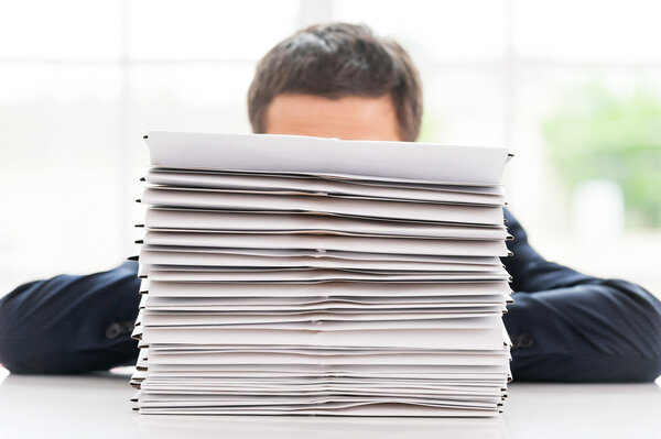 Businessman hiding behind stack of documents