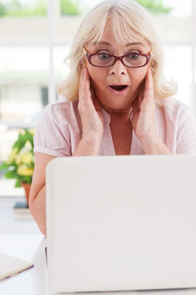 Возбужденная пожилая женщина смотрит на ноутбук — стоковое фото