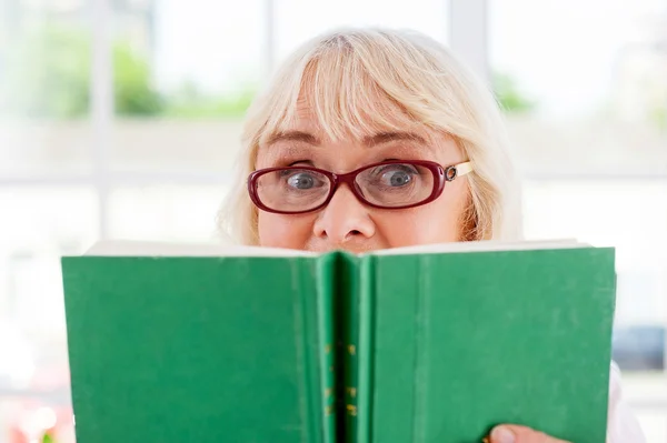 Surprised senior woman holding a book — Stock Photo, Image