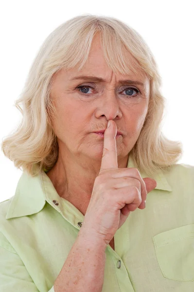 Старшая женщина держит палец на губах — стоковое фото