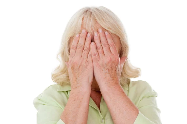 Starszy kobieta obejmujących twarz rękoma — Zdjęcie stockowe