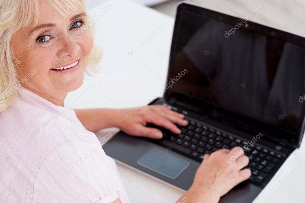 Cheerful senior woman working on laptop
